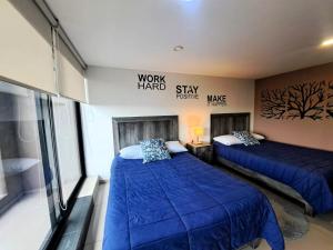 two beds in a room with blue comforter at S07 DOBLE CAMA MATRIMONIAL Premium Suite Frente al TEC CEM con Cocineta WiFi Balcón Parking Terraza in Mexico City
