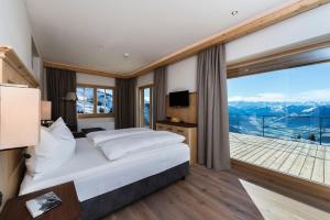 a bedroom with a bed and a large window at BichlAlm Berggasthof in Kitzbühel