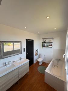 ein Badezimmer mit zwei Waschbecken und einer Badewanne und einer Toilette in der Unterkunft Charmante Maison Néo-bretonne in Perros-Guirec + 6 Fotos