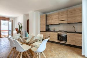ポルト・トッレスにあるLuxury House Porto Torres Centerのキッチン(ガラステーブル、白い椅子付)