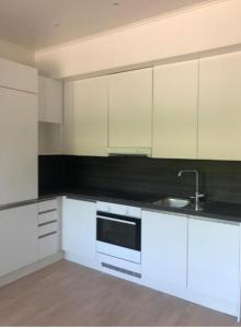a kitchen with white cabinets and a sink at Huoneisto terassilla & parkkipaikalla in Espoo