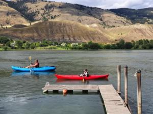 two people in kayaks on a lake next to a dock at Private Bedroom at Riverfront House in Kamloops