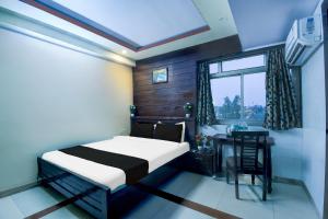 a bedroom with a bed and a desk and a window at Hotel O Bellrose in Jaipur