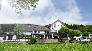 a large white house with a car parked in front of it at Hotel Schweinsberg in Lennestadt