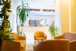 a waiting room with yellow chairs and plants at Hotel Darina in Târgu-Mureş