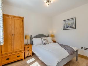 een slaapkamer met een bed en een houten kast bij Cathill Cottage in Creech Saint Michael