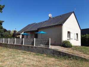 a white house with blue umbrellas in front of it at Camping Onlycamp les Bords de Vienne in L'Ile-Bouchard