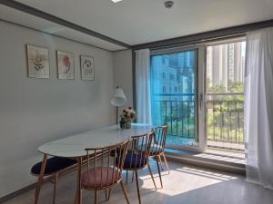 a dining room with a table and chairs and a large window at Eumm stay in Cheongju