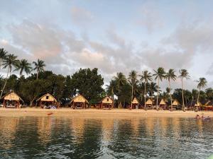 a beach with a group of huts and palm trees at Calilayan Cove Beach Resort in Unisan