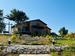 a house on a hill with a stone wall at Wooden Villa Sormoni in Tskaltubo