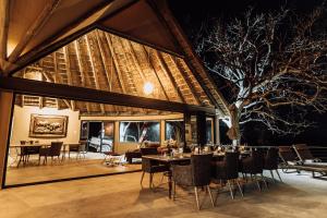 a dining room with tables and chairs and a tree at Kifaru Luxury Lodge in Outjo