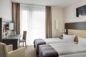 a hotel room with two beds and a desk at IntercityHotel Bonn City in Bonn