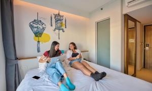 due ragazze sedute su un letto con i loro computer portatili di Lub d Phuket Patong - Near Patong Beach & Vibrant Social Vibe a Patong Beach Altre 39 foto