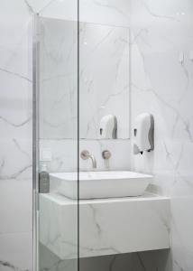 biała łazienka z umywalką i lustrem w obiekcie Superior Suite by Acropolis Cozy Suites w Atenach