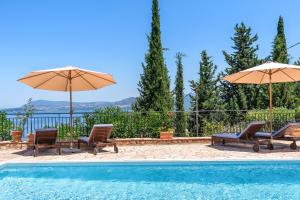 a swimming pool with two chairs and umbrellas at Villa Fortuna in Nikiana