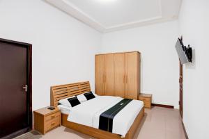 a bedroom with a bed and a tv in it at Hotel O Balikpapan near Taman Beruang Madu formerly Palm Cafe Inn in Balikpapan +23 photos