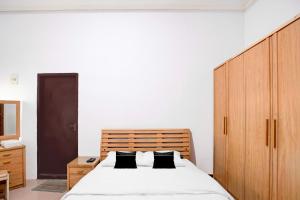 a bedroom with a large bed and a wooden cabinet at Hotel O Balikpapan near Taman Beruang Madu formerly Palm Cafe Inn in Balikpapan