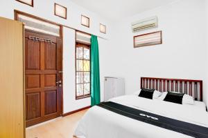 a bedroom with a bed and a wooden door at Hotel O Balikpapan near Taman Beruang Madu formerly Palm Cafe Inn in Balikpapan
