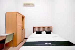 a bedroom with a bed and a desk and a cabinet at Hotel O Balikpapan near Taman Beruang Madu formerly Palm Cafe Inn in Balikpapan