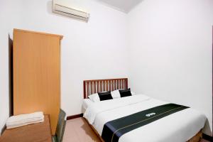 a bedroom with a large white bed with black pillows at Hotel O Balikpapan near Taman Beruang Madu formerly Palm Cafe Inn in Balikpapan