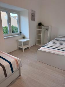 a white bedroom with a bed and a window at Holiday home Omišalj in Omišalj