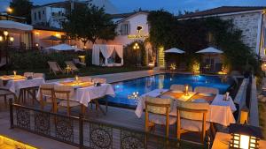 a restaurant with tables and chairs next to a swimming pool at Cunda Ömer Ağa Konağı in Cunda