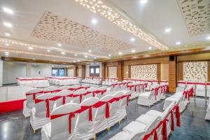 una sala conferenze con sedie bianche e accenti rossi di Prakruti Resort a Vadodara Altre 60 foto
