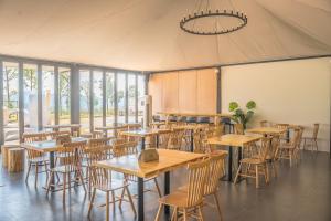 a restaurant with tables and chairs in a tent at Shanyin Xijiang Rustic Luxury Resort Hotel in Bailian