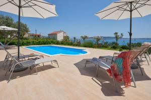 um pátio com cadeiras e guarda-sóis e uma piscina em Villa Mila Trogir em Trogir