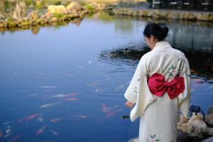 a woman in a kimono standing in front of a pond at Kobi Onsen Resort Hue, Affiliated by Melia in Hue