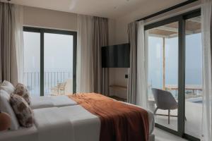 a bedroom with a bed and a balcony with a view at Cavo Marelia in Amoopi