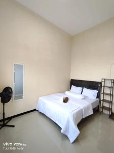 a bedroom with a white bed with a cat laying on it at Villa Putih O3 in Batu +24 photos