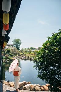 a woman with an umbrella standing next to a river at Kobi Onsen Resort Hue, Affiliated by Melia in Hue +137 photos