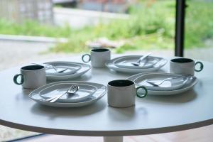 a table with plates and forks and mugs on it at Hokuto Cottage BLUBLU - 北杜コテージ ブルブル - in Hokuto