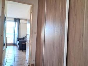 a hallway with a wooden door and a living room at appartement T2 climatisé résidence azur 219 in Le Lavandou