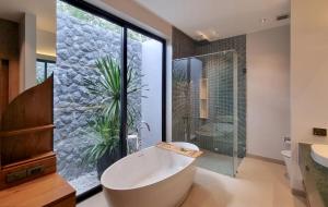 La salle de bains est pourvue d'une grande baignoire et d'une plante. dans l'établissement Bougainvillea Luxury Pool Villas, à Ban Pak Lak 69 autres photos