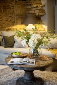 a table with a vase of flowers and a book at Luxury Cotswold Retreats in Moreton in Marsh