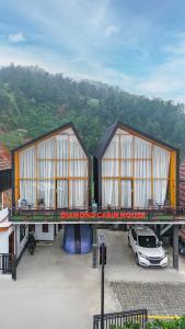 two buildings with a car parked in a parking lot at Diamond Cabin House in Dieng