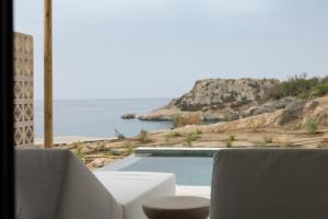 a swimming pool with two chairs and a view of the ocean at Cavo Marelia in Amoopi