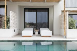 two white chairs next to a swimming pool at Cavo Marelia in Amoopi