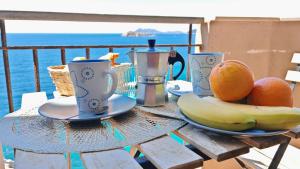 a table with two cups and fruit on it at Appartamento Blu Mare in Teulada +20 photos