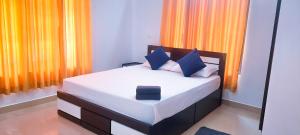 a bedroom with a bed with blue and orange curtains at Sands Villa Homestay in Wayanad