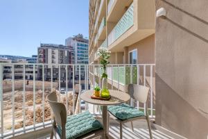 a balcony with a table and chairs and a view of the beach at Cozy Apartment Heart of St Julians Sleeps 5 in San Pawl il Bahar