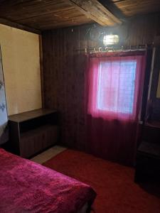 a bedroom with a red bed and a window at Veski talu aidamaja 