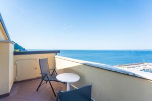 ApartmentsGarda - Baia Del Garda 5 في غارْدا: شرفة مع طاولة وكراسي والمحيط