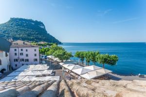 ApartmentsGarda - Baia Del Garda 5 في غارْدا: اطلالة على شاطئ فيه مظلات بيضاء والمحيط