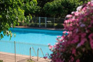 une piscine avec une clôture et des fleurs roses dans l'établissement Castel Novel Cottage, à Varetz