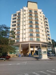 een groot wit gebouw met een parkeerplaats ervoor bij Marina sunset view in Lumut