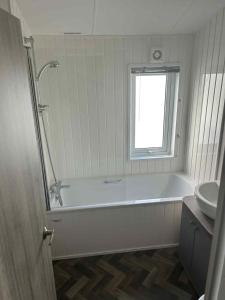 a bathroom with a bath tub and a sink at Clearwater Lodge in Lossiemouth +16 photos