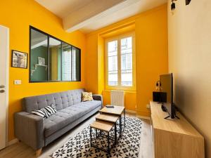 a living room with yellow walls and a gray couch at T2 Centre Riom 3 Personnes in Riom